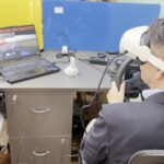 A trainee in a VR headset at a steering wheel, driving the simulation in the HapzXR studio